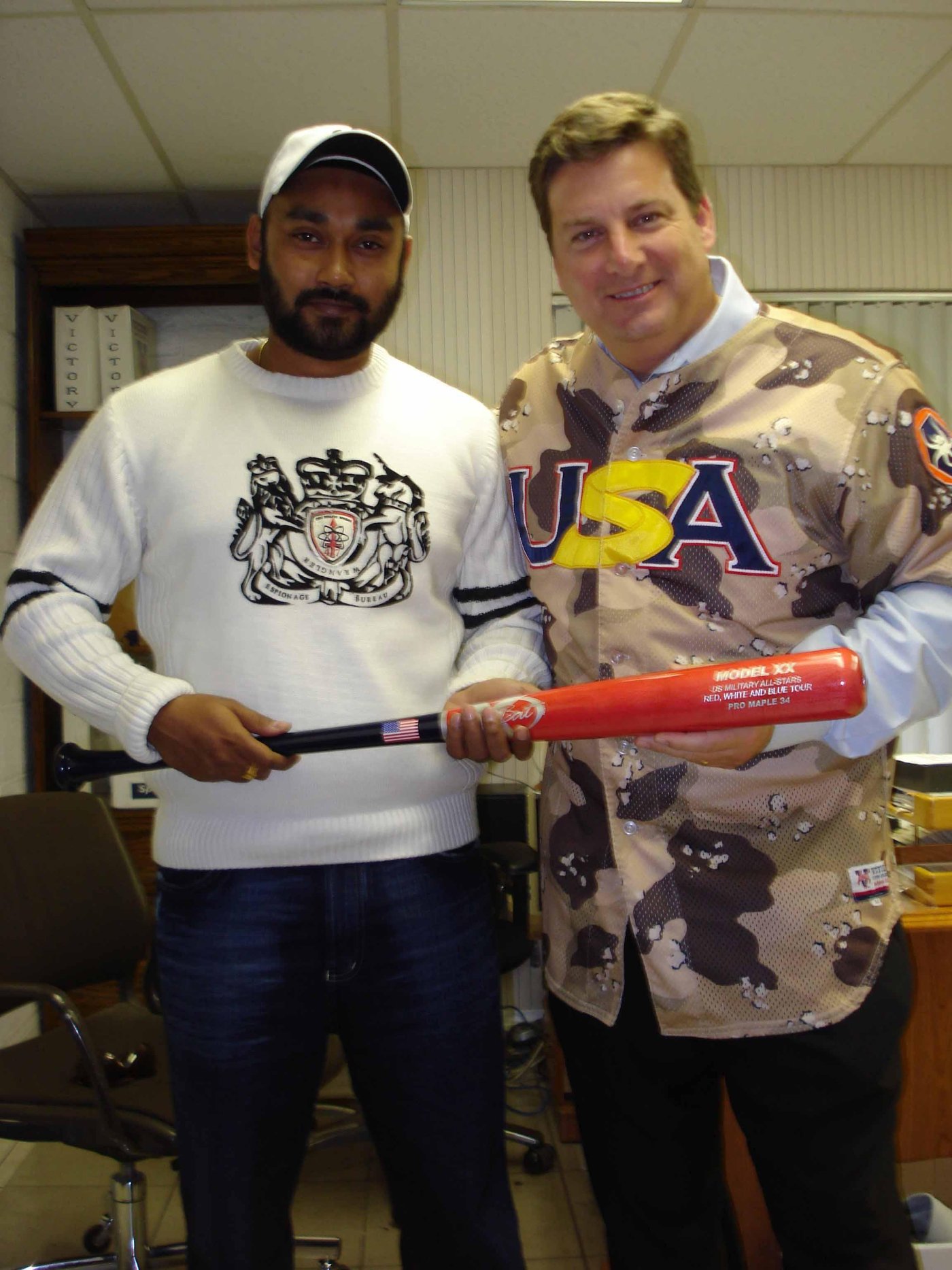 Rickey Singh receiving a commemorative U.S. Military All-Stars tour bat from LCDR Terrence Allvord